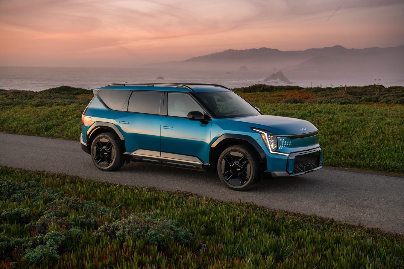 Official Kia EV9 exterior press image photographed at golden hour on a coastal road