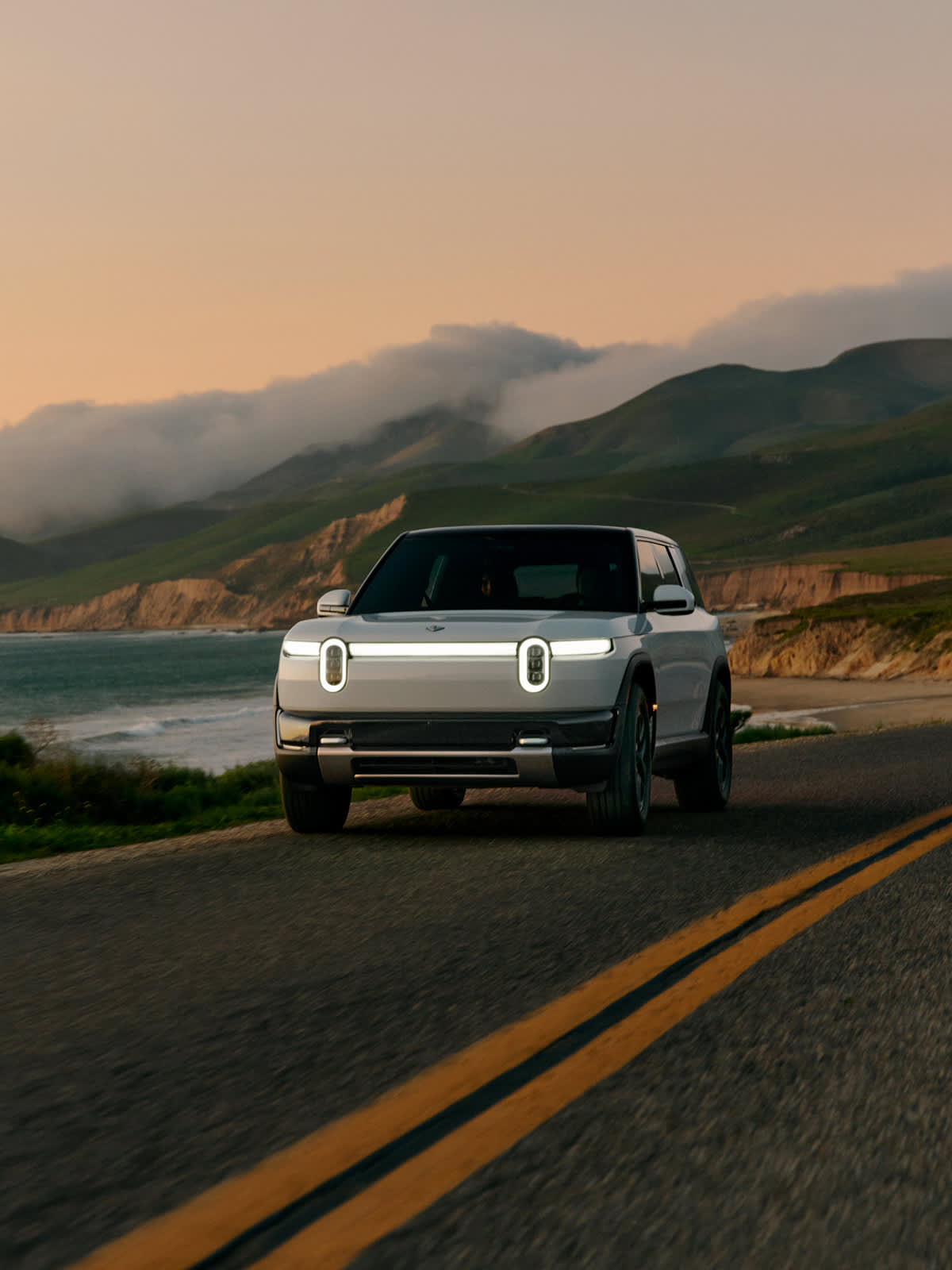 Official Rivian image of the R2 electric SUV driving on a mountain road