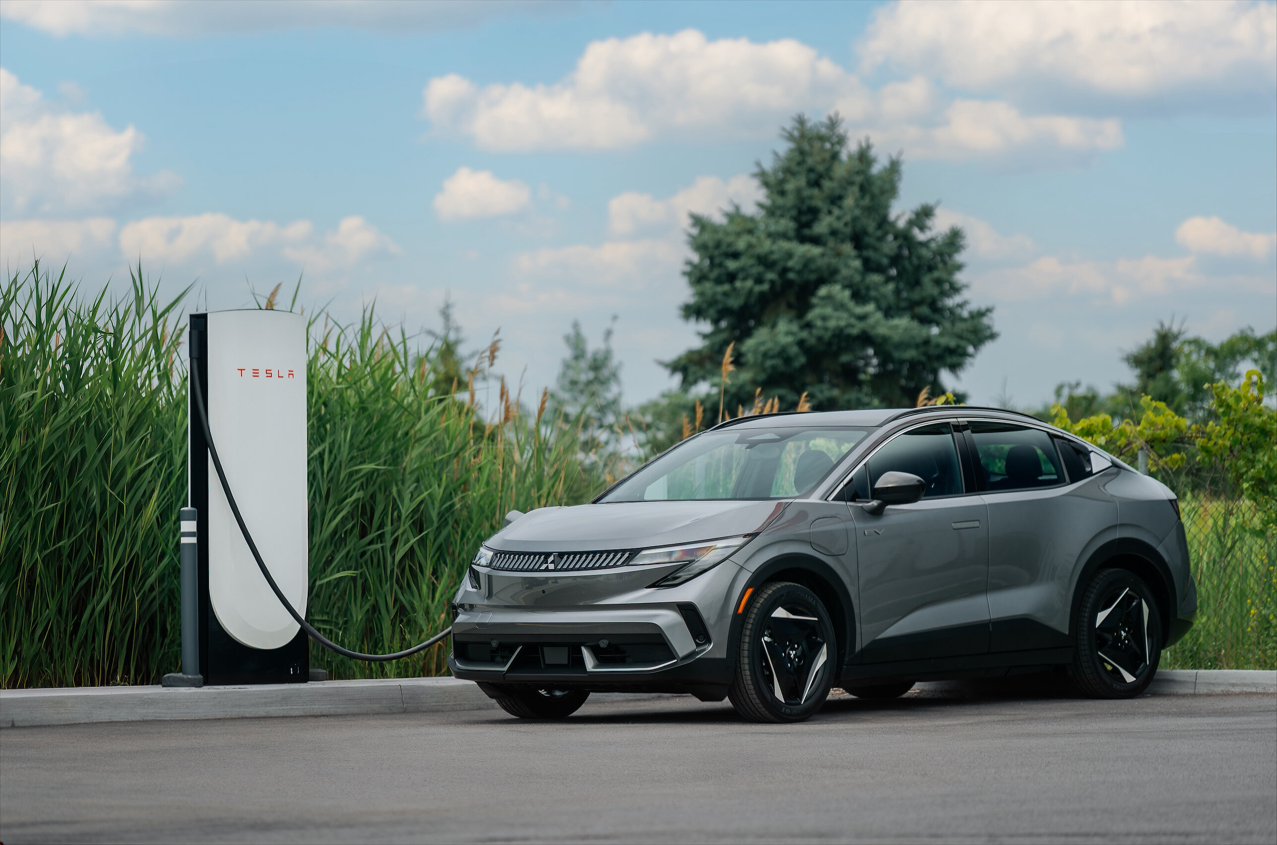 Silver Mitsubishi Eclipse Sportback connected to a Tesla Supercharger