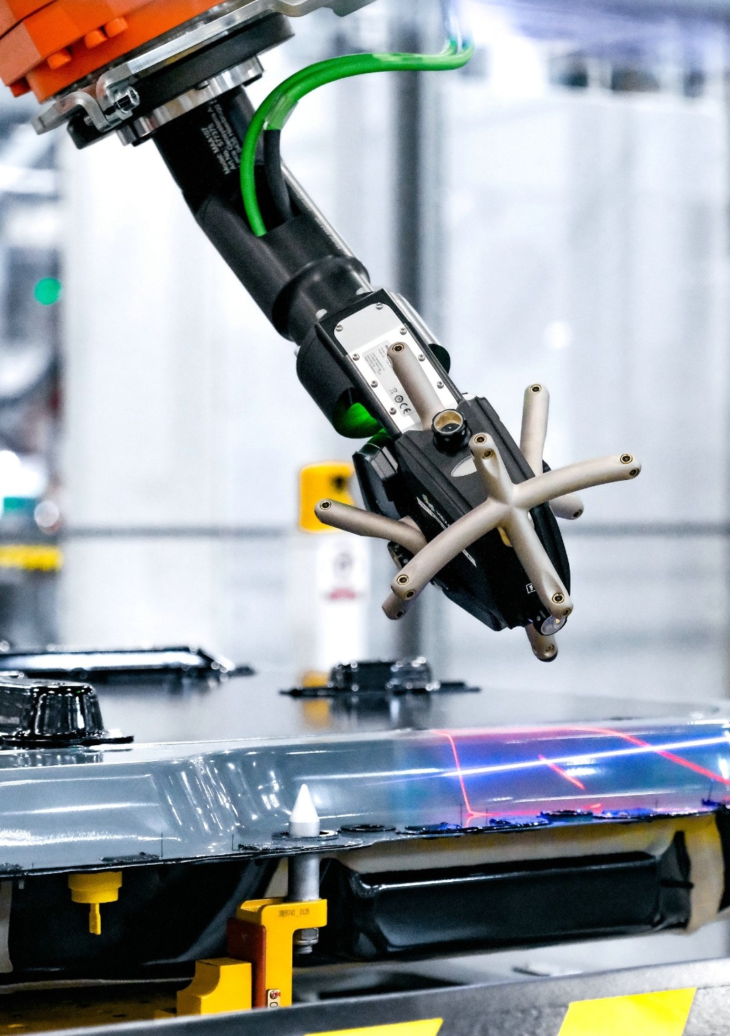 Robotic production equipment above a battery housing with visible light lines