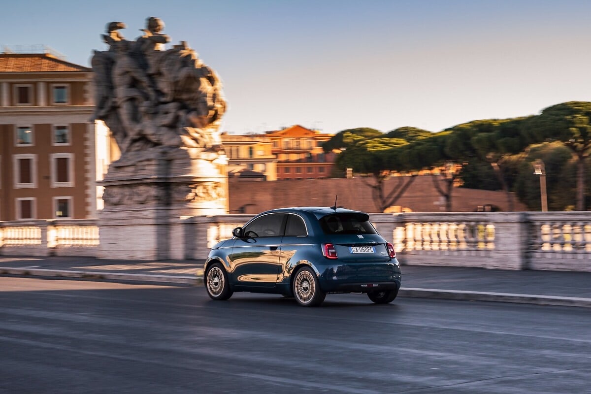 Blue Fiat 500e driving past historic buildings in Rome