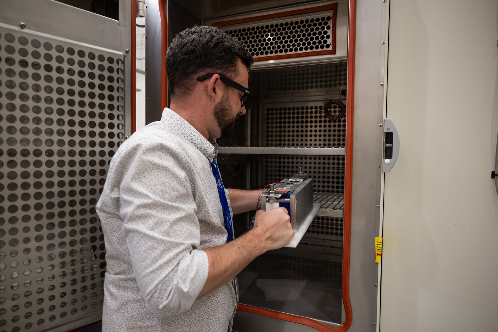Official Ford image of a battery technician placing a battery module into a climate-test chamber
