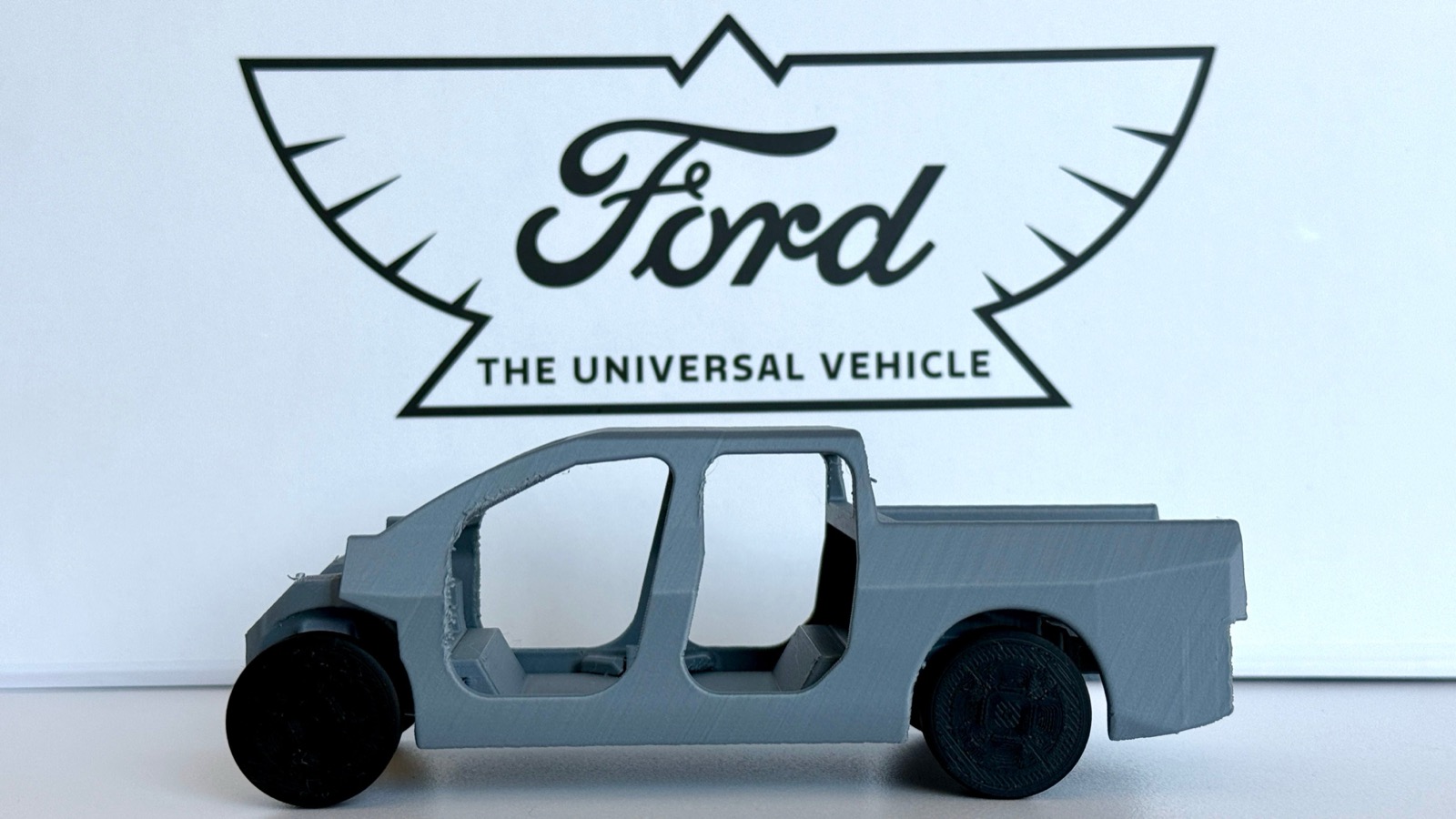 3D-printed model of Ford's Universal EV pickup program shown in front of a Ford Universal Vehicle display