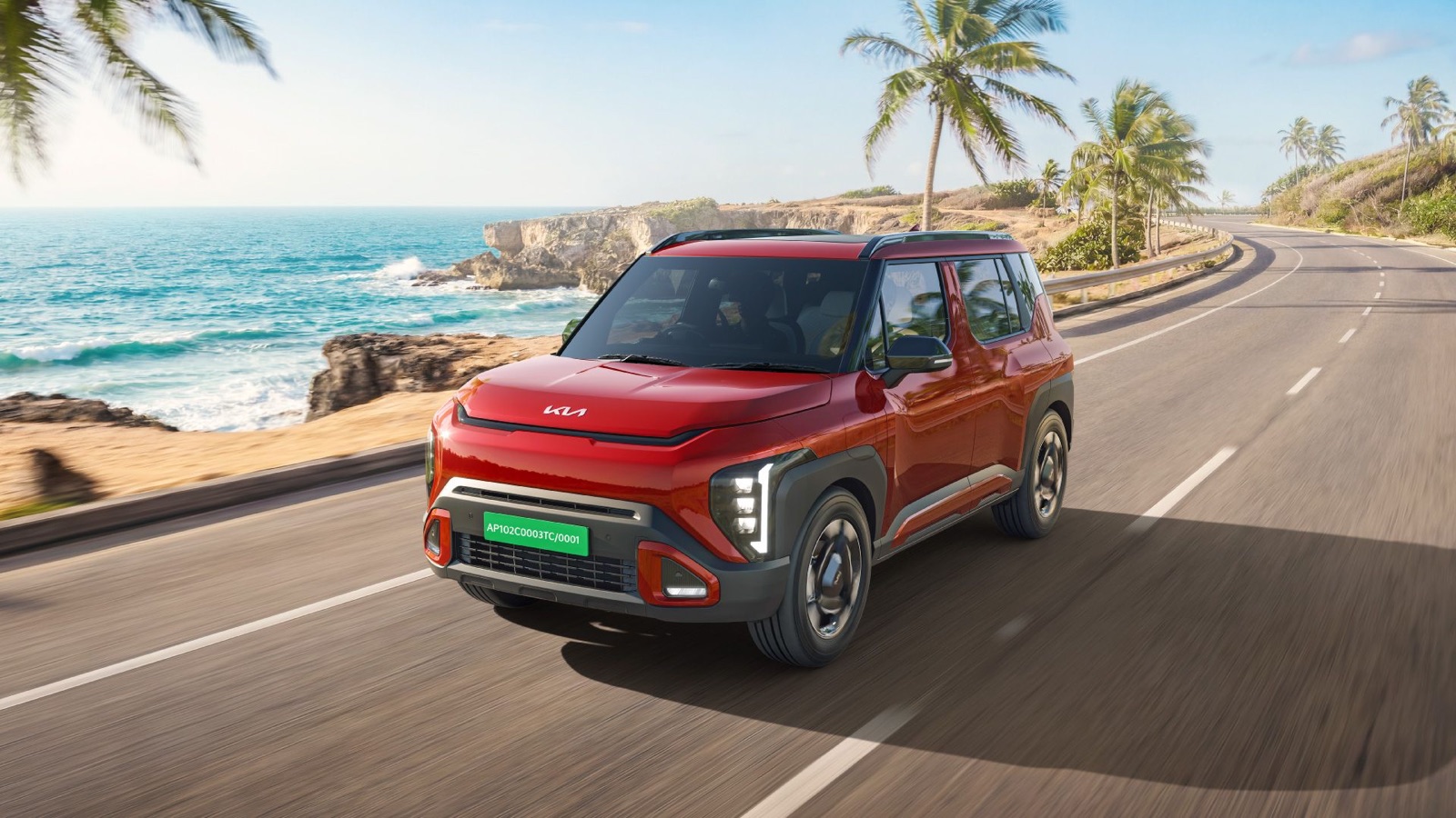 Red Kia Syros EV driving on a coastal road