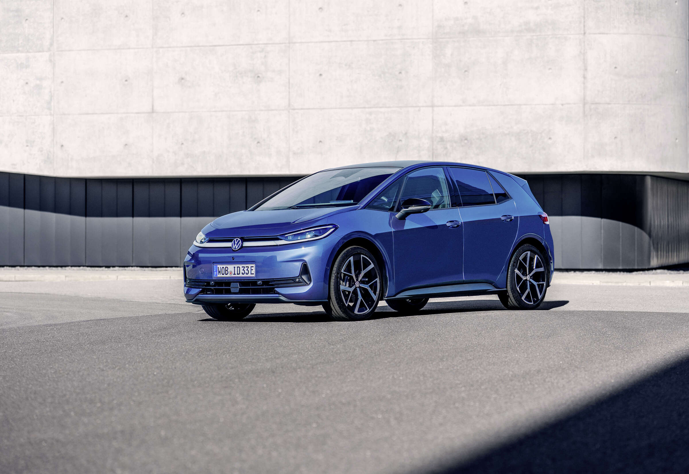 Volkswagen ID.3 Neo official exterior image parked beside a modern concrete building